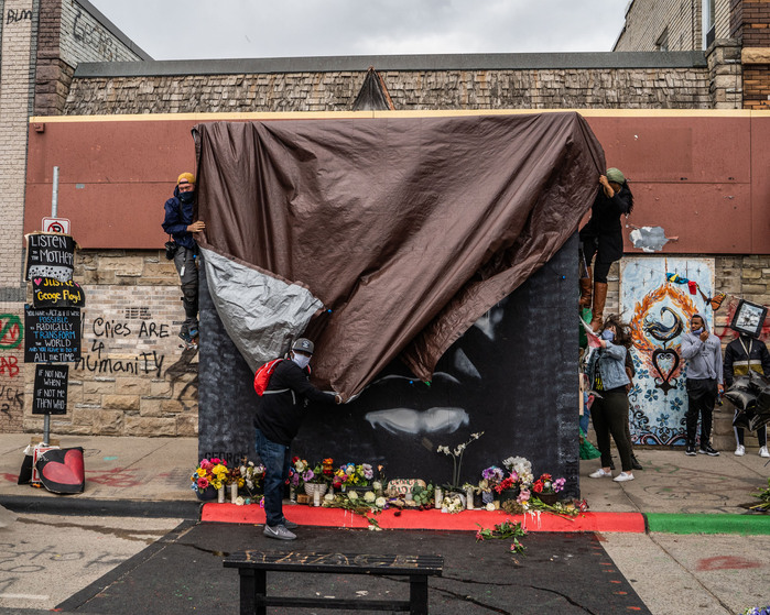 "Icon of a Revolution," the painting of George Floyd by artist Peyton Scott Russell, is quickly covered in a tarp as a storm blows in at George Floyd Square on Sunday, April 18, 2021.