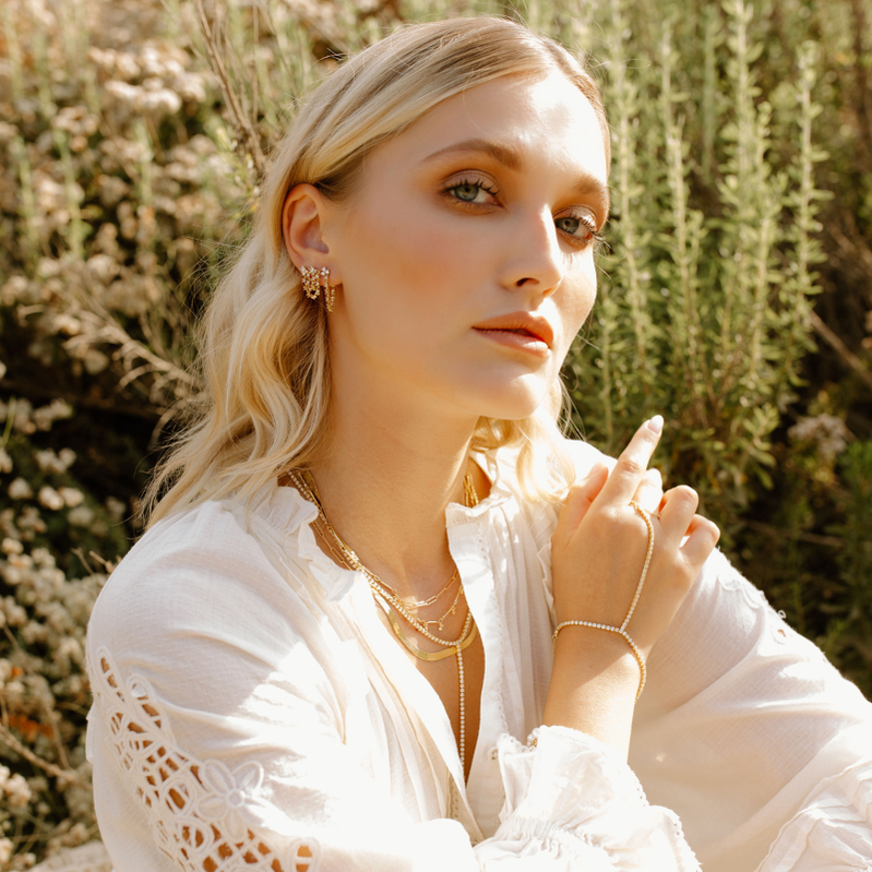 Girl in wildflowers showing jewelry.