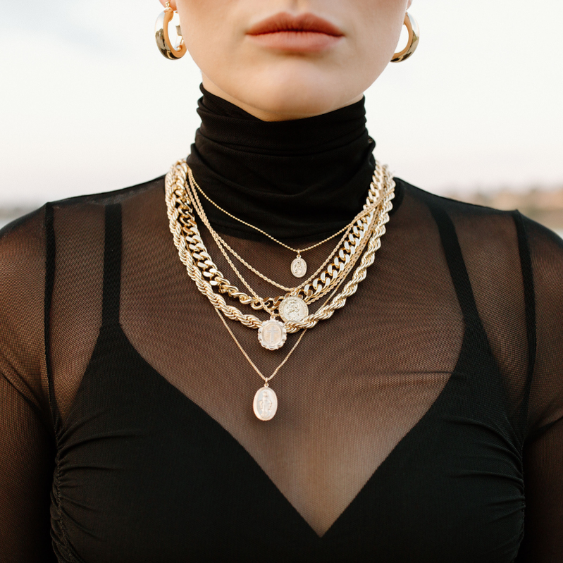 gold jewelry on a girl wearing black sheer top.