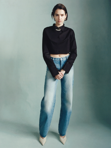 Girl wearing DL1961 jeans and a black sweater with her hands crossed.