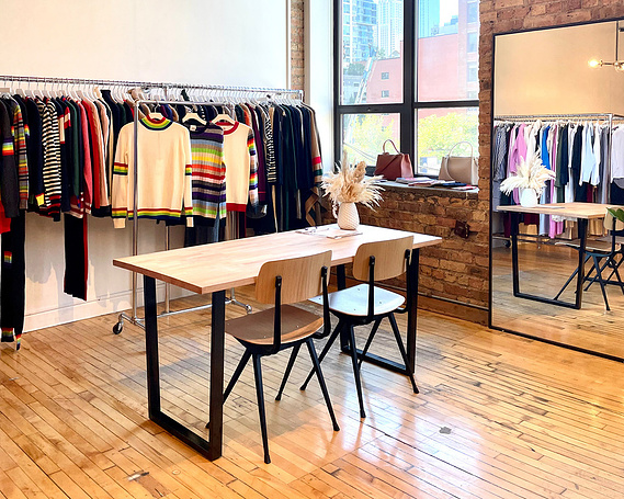 Pivet Showroom clothing collection on rack next to a work desk and large window.