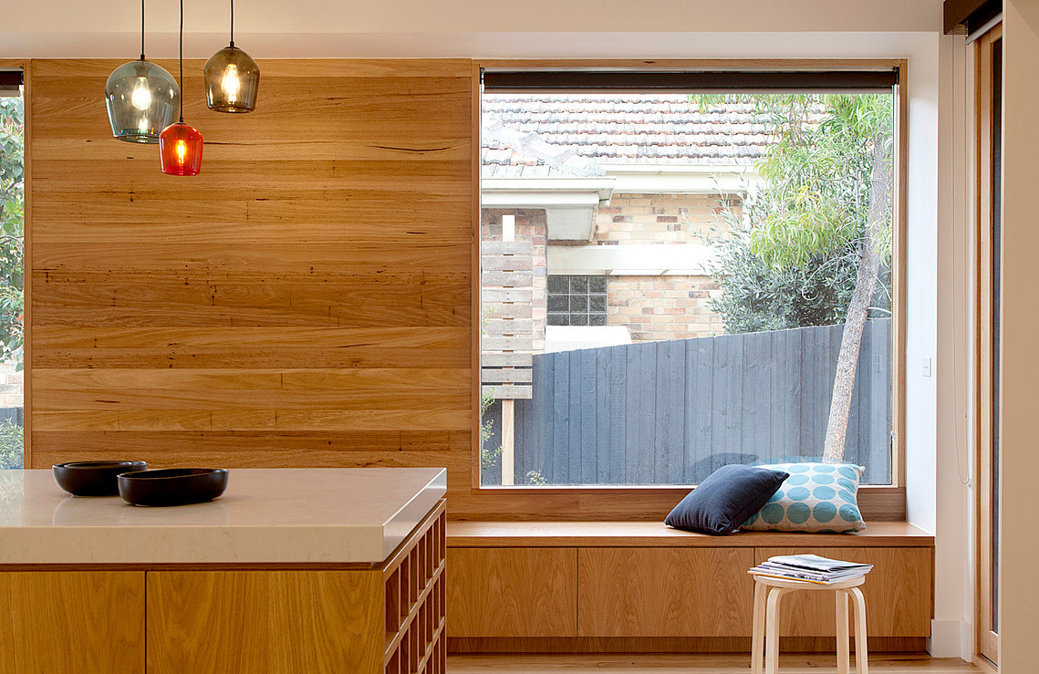 A new kitchen dining space was created within a renovated house. Natural finishes were used on the timber wall. Locally hand made glass lights hang in the distance