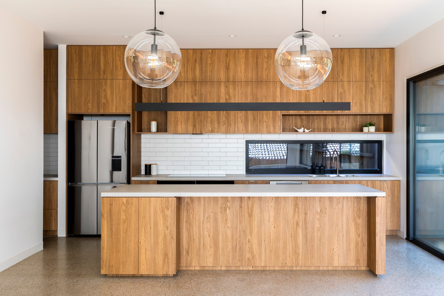 A kitchen with natural finishes of timber veneer, polished concrete and subway tiles feature in this all electric 7 star rated house.