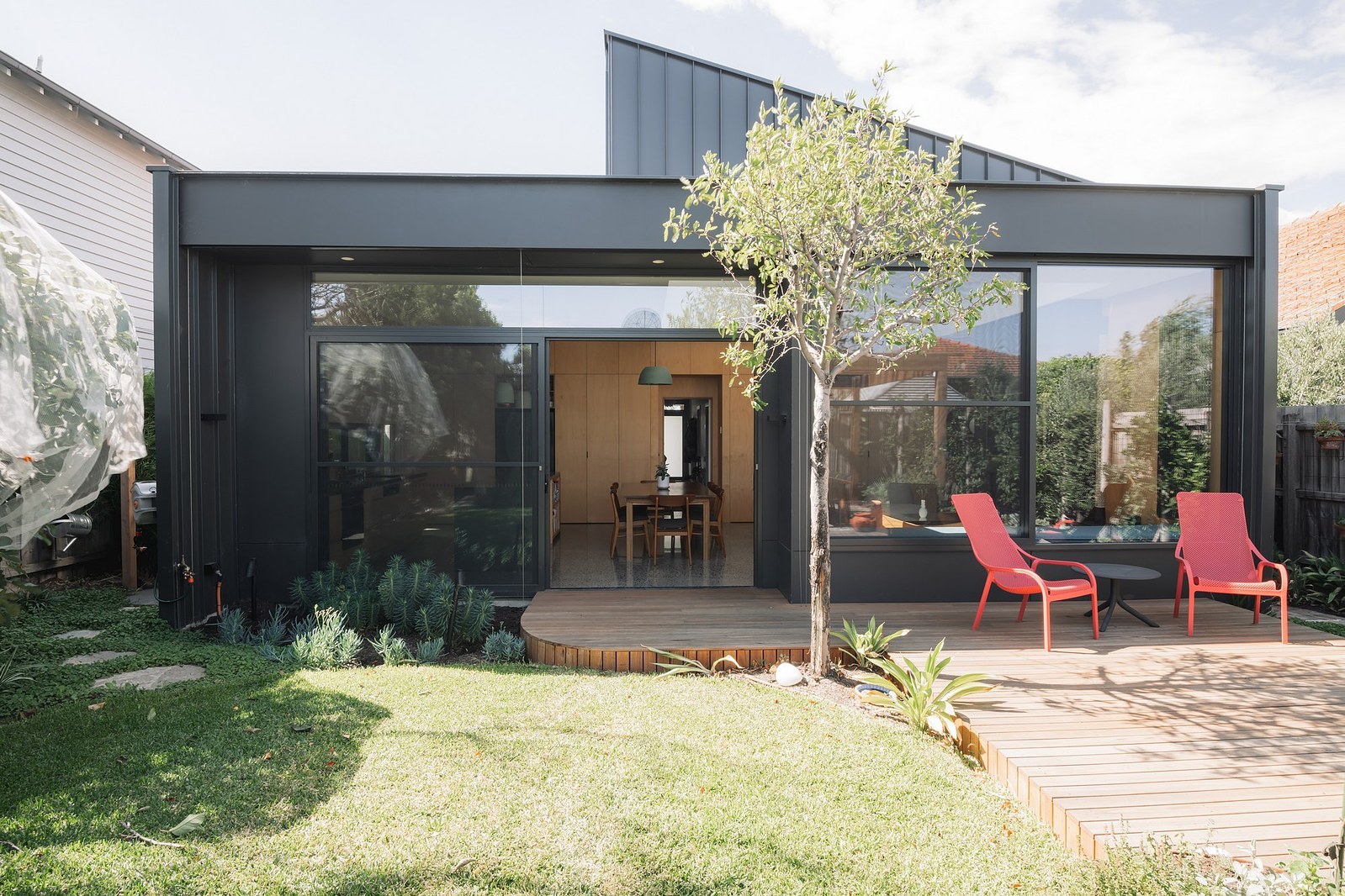New building facade with upper windows, large expanse of glass and landscaping
