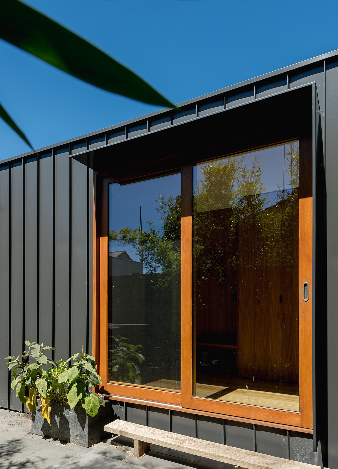 Large north facing timber doors within a black metal clad wall. There is a small step from beyond the door that leads to outside.