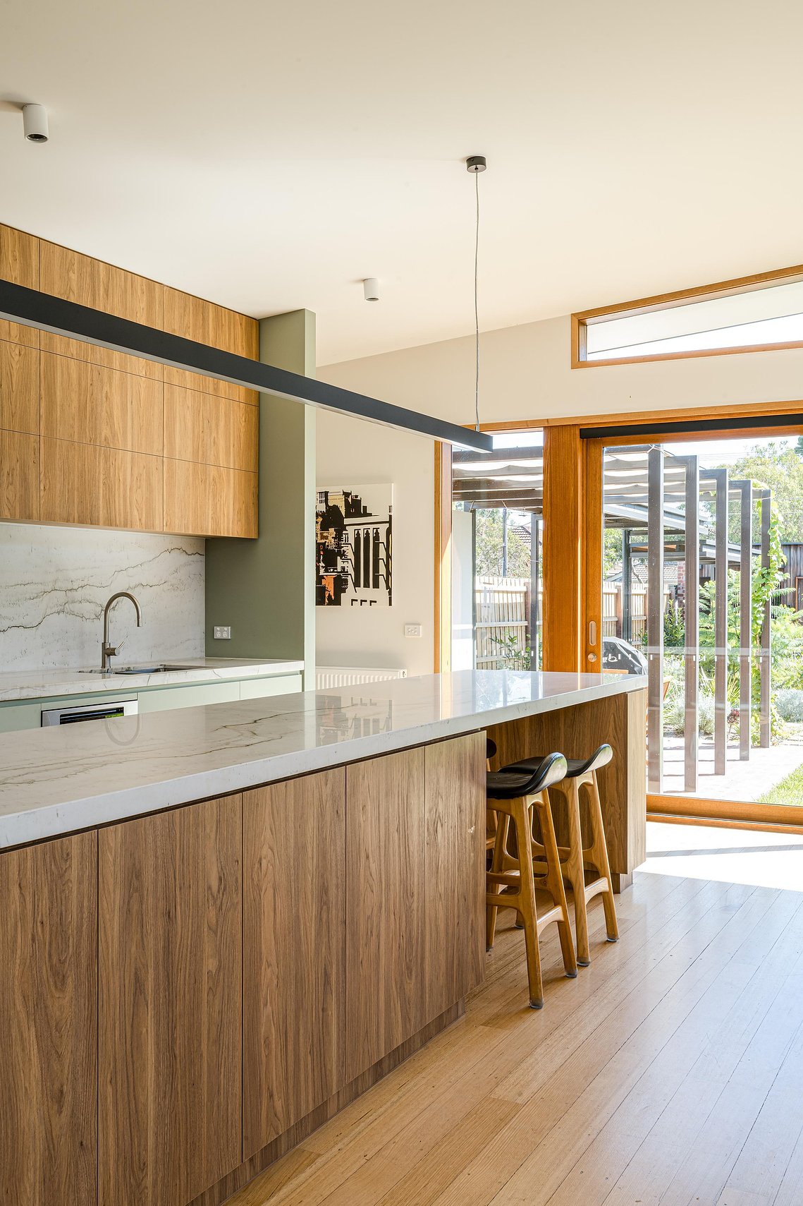 Large north facing windows let ample light into a kitchen area with and island bench and bench seats. Sustainable living in Brunswick
