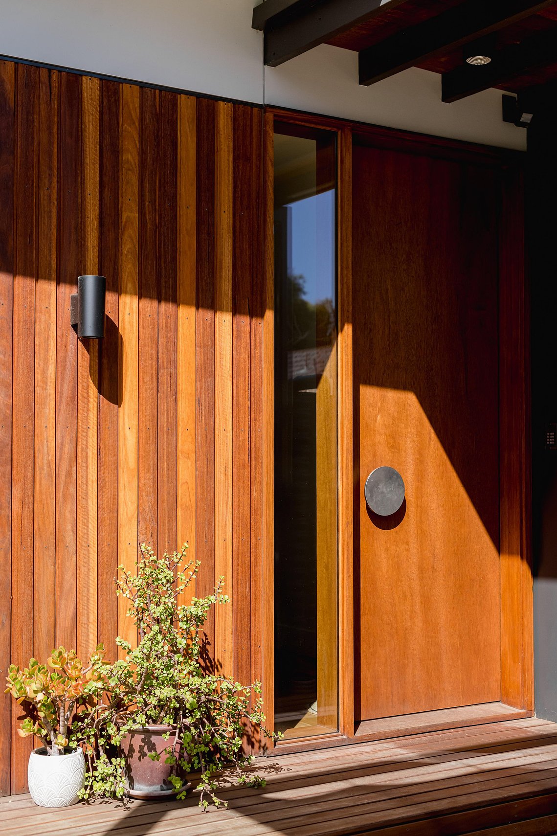 New front door with circular metal door handle.  The entry into this new house has timber cladding to the side. Sustainable living Brunswick