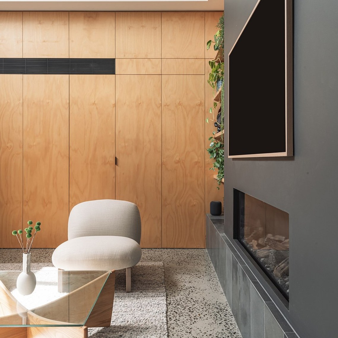 A cosy seat adjacent to a glass table with green billy button flowers makes this new living space feel enticing.