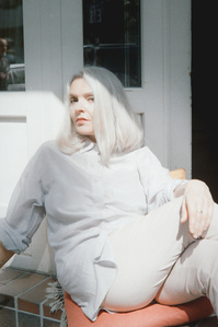 Female best ager model wearing a light grey silk shirt by Marlena Frank. Long grey hair, muted colors on Wolfen NC500
