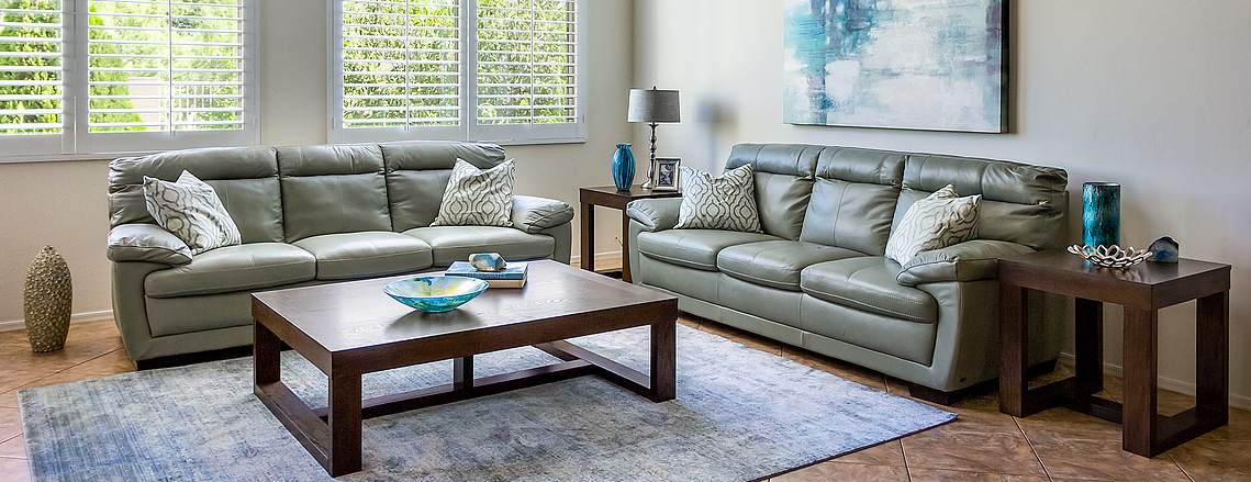 Green leather sofas in this Tucson AZ home with cedar tree views through hi-end shutters.  