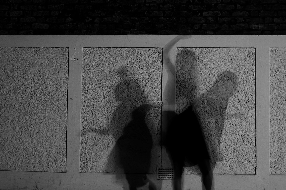 Shadows - Collaboration with Ned Summers 
Black and white image of abstract figure in black dress, with shadows in three positions moving across the frame. Figure against a white textured wall background.
