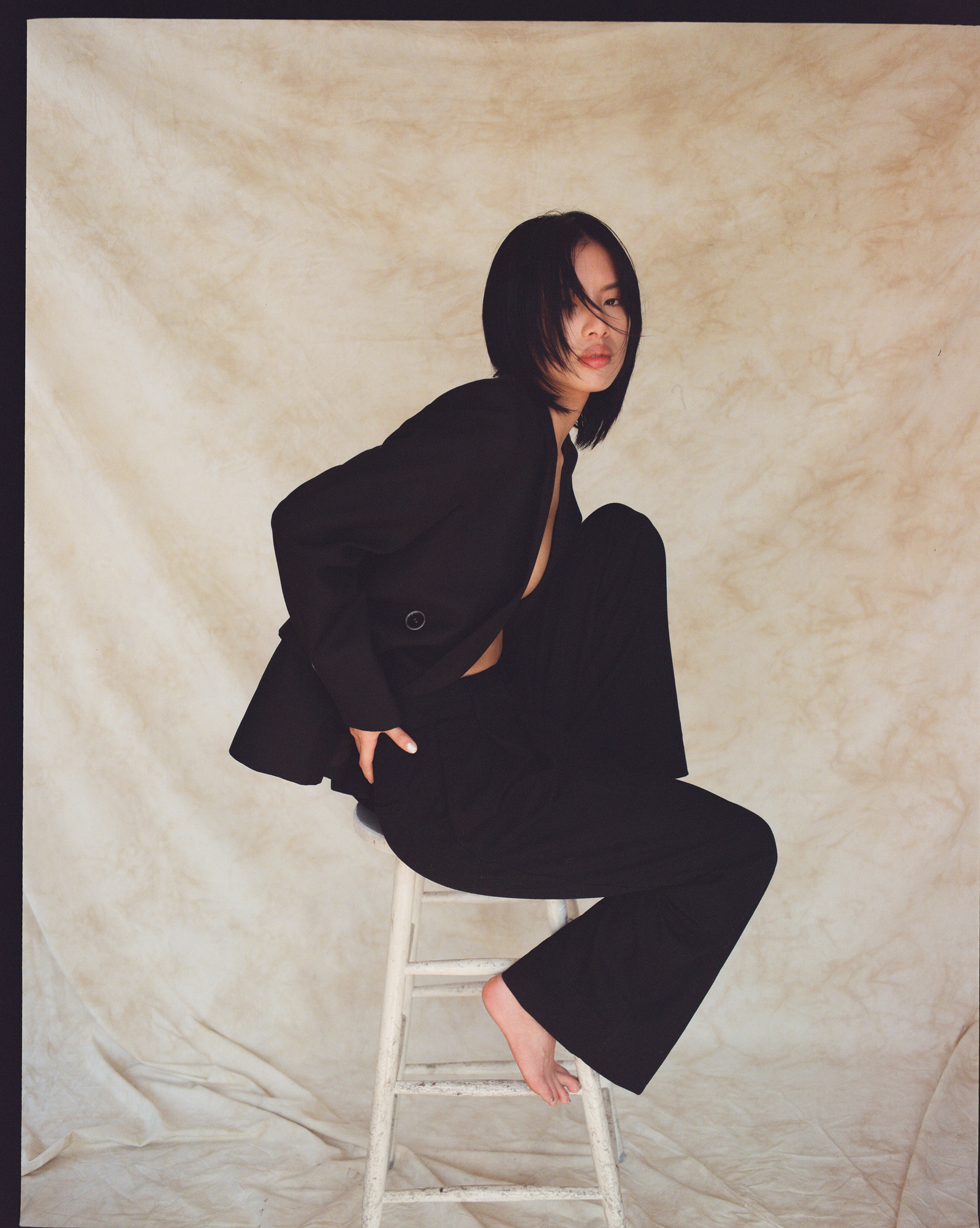 girl in front of draped backdrop in photography studio sitting on stool new york city