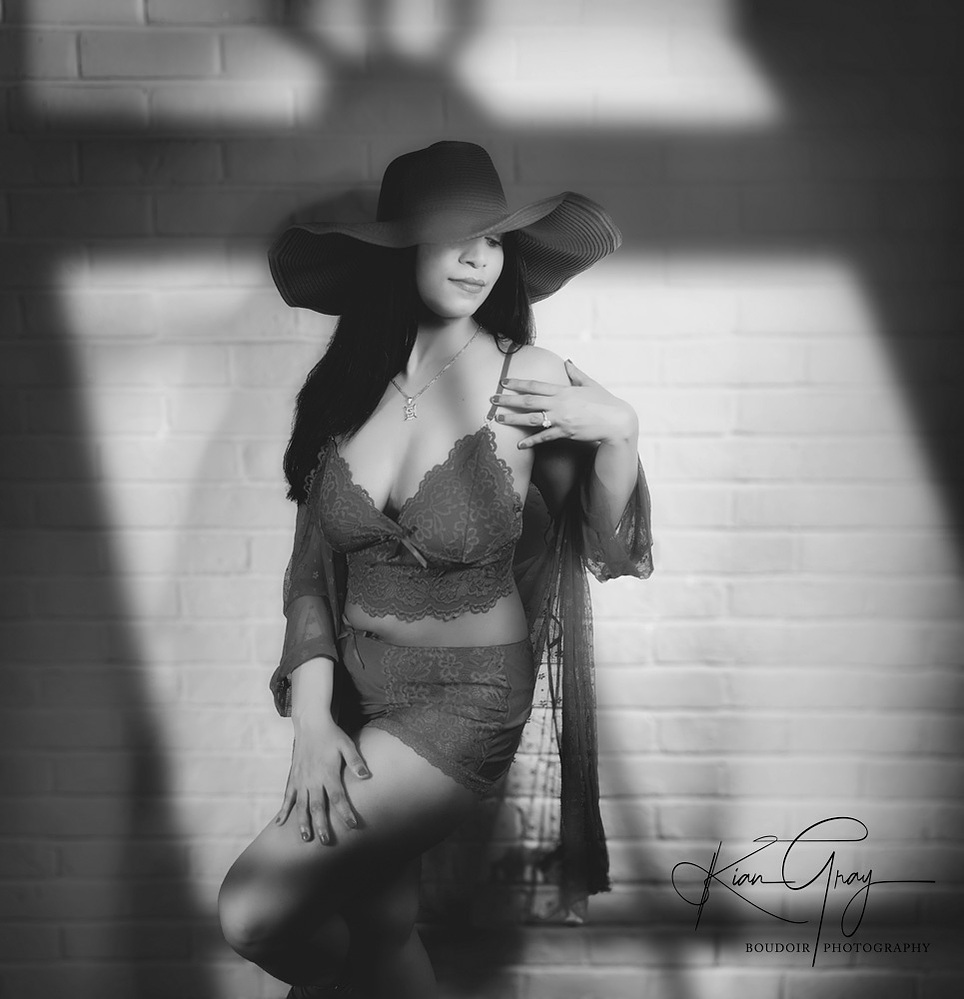 A stylish monochrome boudoir portrait with intentional lighting and shadow textures, capturing timeless feminine allure.