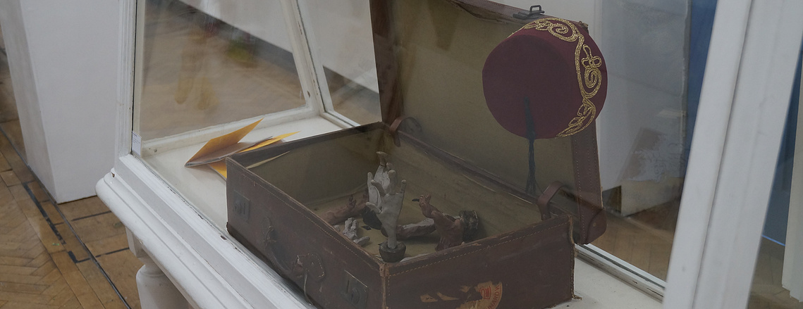 Suitcase with monkey paw sculptures referenced in pop culture displayed in a vitrine