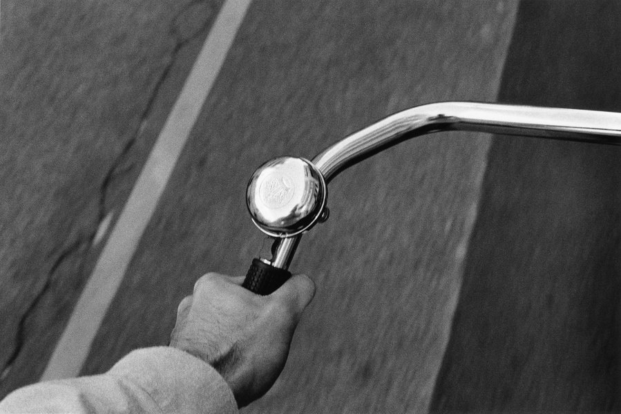 Black and white photograph of a person holding onto a bicycle with a bell 