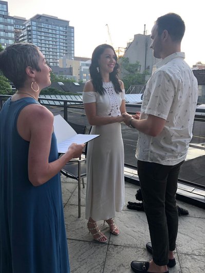 A wedding officiant marrying a couple on a rooftop deck.