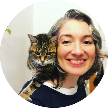 Molly smiling directly at the camera with a cat sitting on her shoulders.