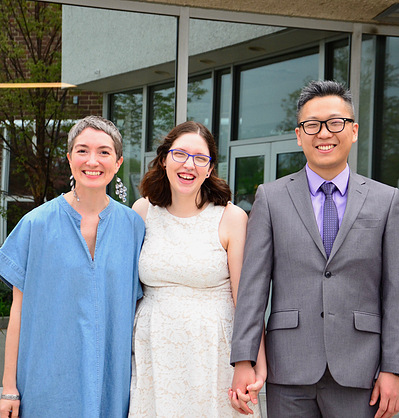 A wedding officiant posing and smiling with newlyweds.