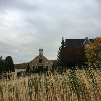 A small chapel and winery on a hill on an overcast day with golden grass in front.