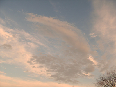 Pinkish clouds on a blue sky with a hint of tree in the corner.