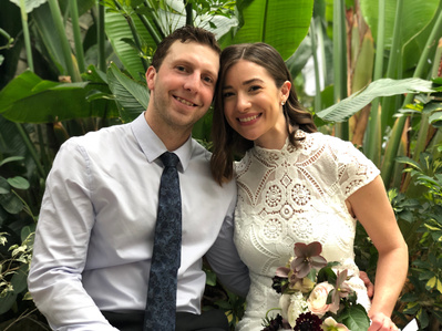 Two newlyweds posing for a photo in a greenhouse.