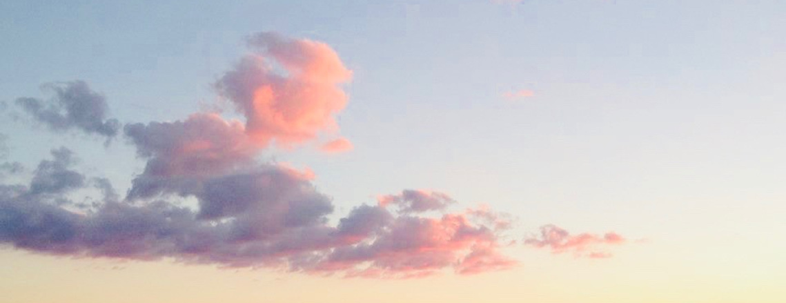 Pink and blue fluffy clouds clouds against an ombre sky.
