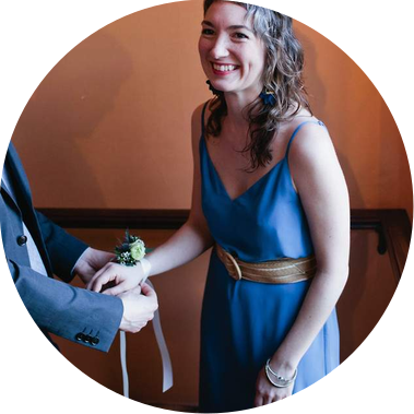 Molly wearing a blue dress and smiling as an unseen person ties a corsage tied around her wrist.