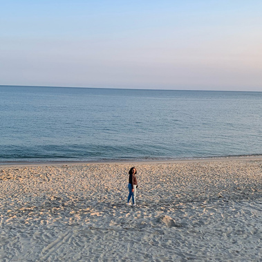A woman walking on the beach and turning back toward the camera