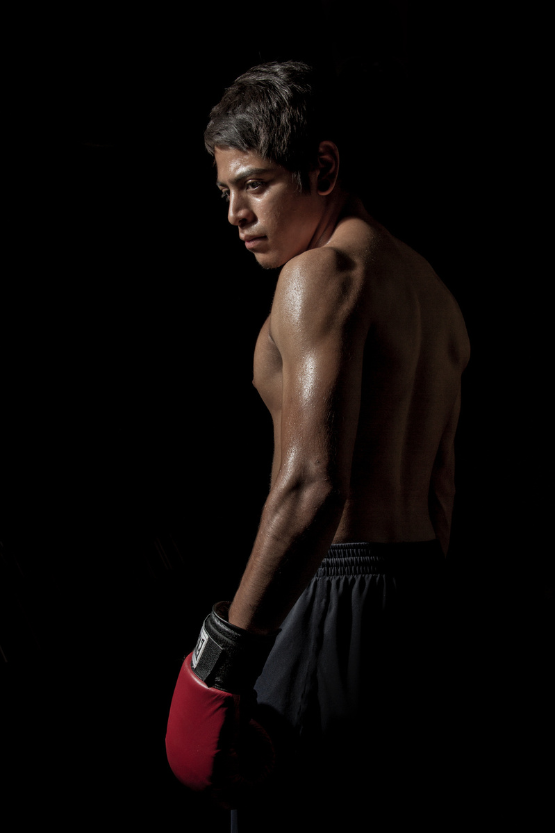 Photo of boxer standing shirtless in dramatic lighting photo by Jason Barnes