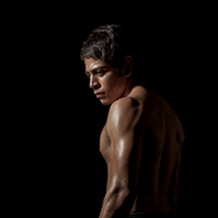 Photo of boxer standing shirtless in dramatic lighting photo by Jason Barnes
