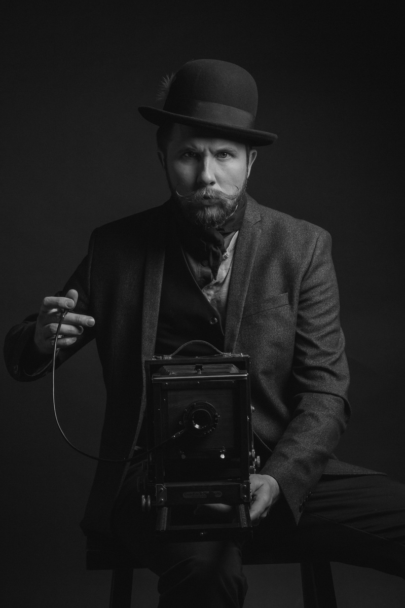 Dramatic portrait of photographer holding vintage 4x5 film camera and taking a picture photographed by commercial and editorial photographer Jason Barnes in San Antonio, TX