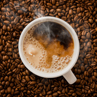 Image of hot steaming coffee being splashed with milk or cream on a bed of freshly roasted coffee beans photographed by Texas-based commercial photographer Jason Barnes
