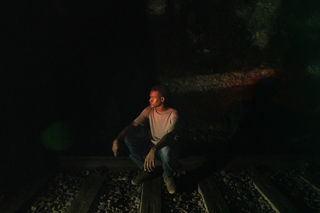 A migrant from sub-Saharan Africa takes a brief pause, sitting on the tracks during the night crossing of a railway tunnel connecting Italy and France. Many migrants choose to cross the Ventimiglia border by walking through the dark railway tunnels.