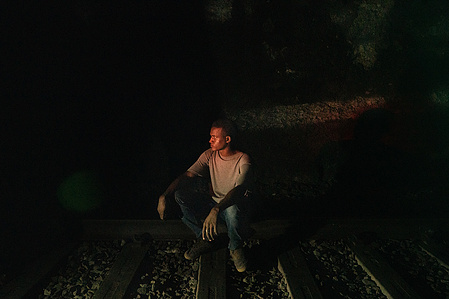 A migrant from sub-Saharan Africa takes a brief pause, sitting on the tracks during the night crossing of a railway tunnel connecting Italy and France. Many migrants choose to cross the Ventimiglia border by walking through the dark railway tunnels.