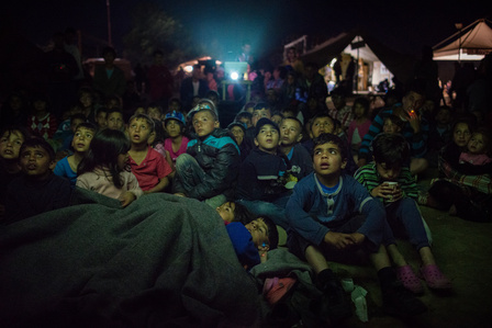 ​A group of international volunteers and Greek activists organizes evening screenings of cartoons to entertain hundreds of minors trapped in the refugee camp of Idomeni.