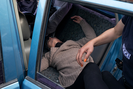 A protester lies on a Greek police car after experiencing a collapse. The woman was taking part in a demonstration calling for the reopening of the borders with Macedonia.