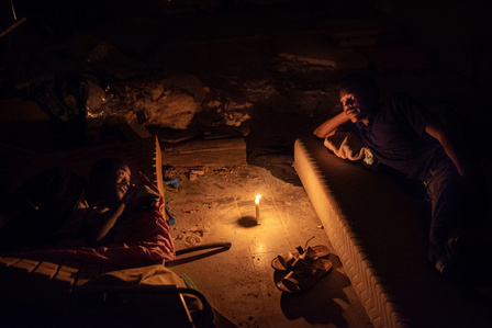 Two migrants from sub-Saharan Africa rest on makeshift beds inside the Baobab Center, a former Eritrean cultural center near Tiburtina station, repurposed as a refuge for migrants in transit from Sicilian hotspots to northern Europe