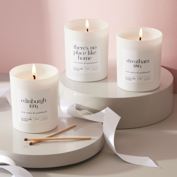 Christmas product photography, personalised candles on a pink background with white ribbon