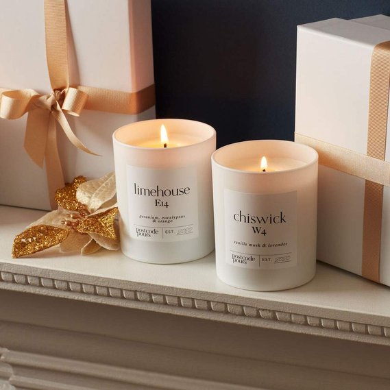 Christmas candle photography of white and gold gift wrapped boxes with two candles on a mantlepiece
