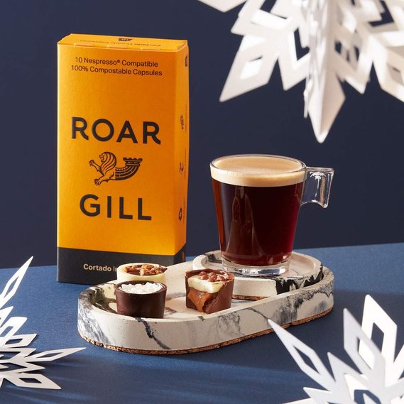 Christmas coffee photography, an espresso glass with chocolates on a navy background with white snowflakes