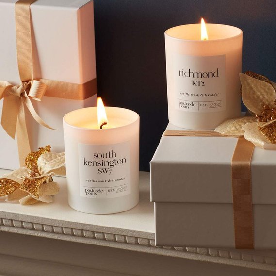 Christmas candle photography of white and gold gift wrapped boxes with two candles on a mantlepiece with Christmas decorations