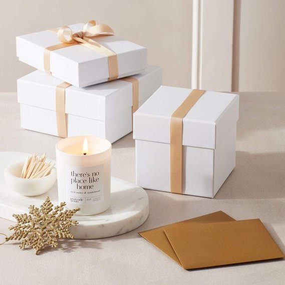 Christmas candle photography of white and gold gift wrapped boxes with a candle and Christmas cards