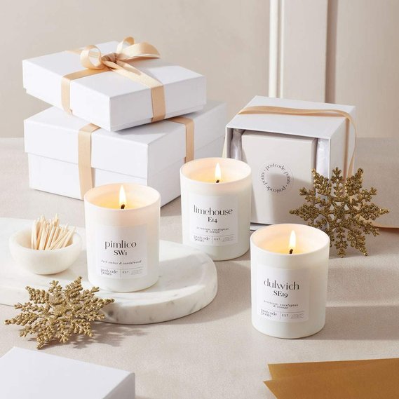 Christmas candle photography of white and gold gift wrapped boxes with three candles and Christmas decorations