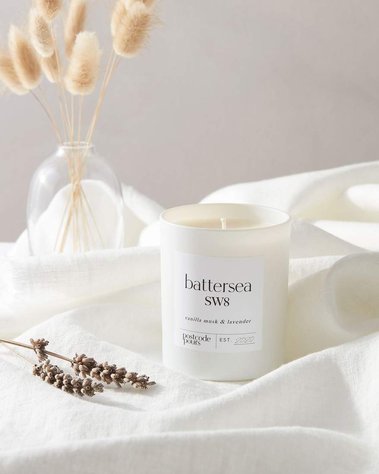 Product photography of a scented candle with ingredients of lavender shown a on white linen background