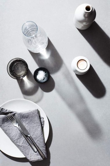 Product photography of a dinner table setting in monochrome on a concrete background.