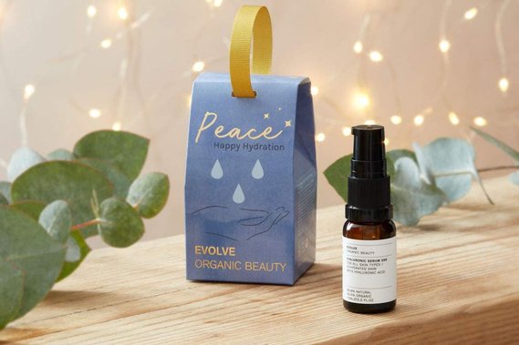 Christmas product photography, skincare product on a wooden shelf with fairy lights and fresh foliage