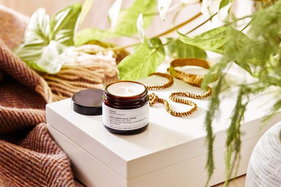 Lifestyle product photography of an open moisturiser jar on a dressing table with houseplants.
