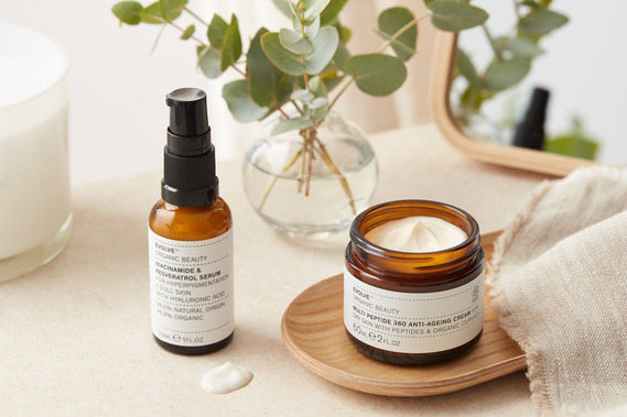 beauty product photography for Evolve beauty products, an open jar of moisturiser and a pump serum bottle on a dressing table with fresh eucalyptus