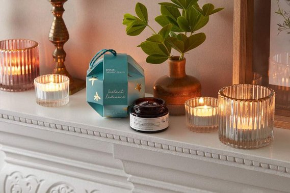 Christmas product photography of a skincare product lit by candle-light on a mantlepiece