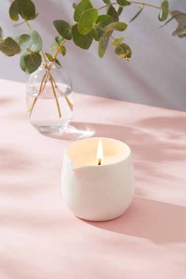 Product photography of a massage candle on a colouful pink background with fresh eucalyptus